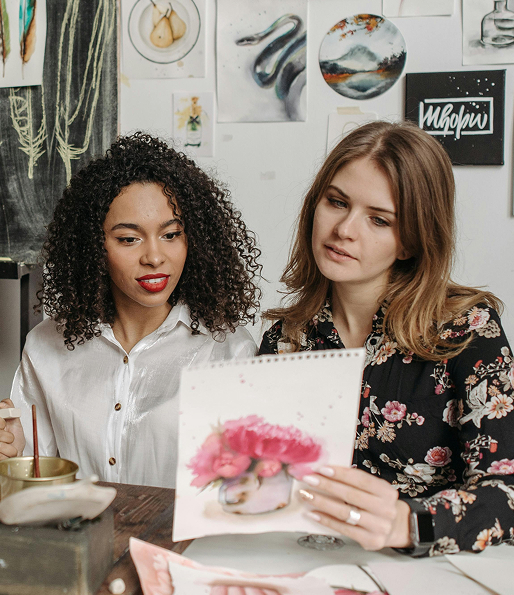 Two women looking at a watercolor painting.
